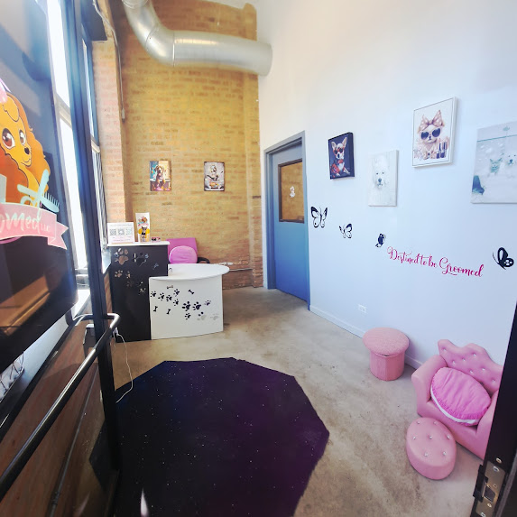 A small, brightly lit office with animal-themed art on the walls, a white desk with pink accents, a pink chair, and a playful pink lips-shaped chair with a matching ottoman. Black butterfly decals decorate the wall.